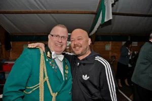 Frater Sebastianus & Afra Schützenbruder bei einer Feier in einem Festzelt in Köln, traditionelle Trachten, fröhliche Atmosphäre, Gemeinschaft.