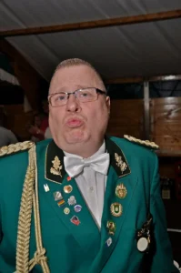 Glamouröser Schützenbruder in traditioneller Uniform mit Pins und Orden bei Sebastianus & Afra Schützenbrauchtum in Köln.