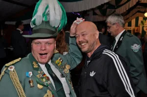 Bayerischer Schützenbruder in traditioneller Uniform mit Orden und Zierrat bei Feierlichkeit.