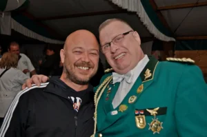 Traditioneller Schützenfest-Teilnehmer in grüner Uniform mit Abzeichen und Orden bei Sebastianus & Afra Schützenbruderschaft.