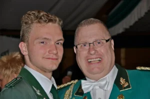Junge und älterer Mann in grünen Schützenuniformen bei einem Fest, lachend und in fröhlicher Stimmung.