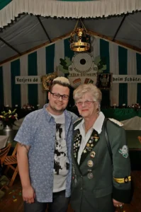 Fröhliches Mitglied der Schützenbruderschaft mit einer älteren Dame in festlicher Uniform bei Schützenfestveranstaltung in Köln-Ostheim.