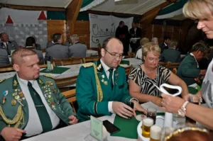 Hochwertige Schützenbrüder in traditioneller Uniform bei festlicher Veranstaltung in der Schützenhalle.