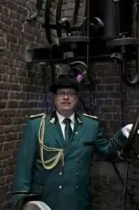 Zünftiger Schützenbruder in traditioneller Uniform vor alter Backsteinmauer bei Sebastianus & Afra Köln.