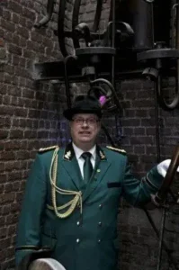 Zünftiger Schützenbruder in traditioneller Uniform vor alter Backsteinmauer bei Sebastianus & Afra Köln.