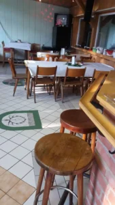 Holzbarhocker stehen in einem Restaurant mit Tischen und Stühlen im Hintergrund.