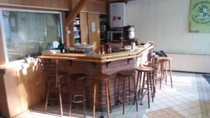 Holztheke mit Barhockern in einem Innenraum, ausgestattet mit verschiedenen Utensilien.