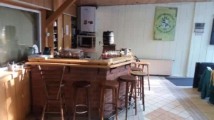 Holzbar mit Hockern und Kücheneinrichtungen im Hintergrund.