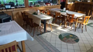 Ein Restaurant mit mehreren Tischen und Stühlen, die mit weißen Tischdecken bedeckt sind.