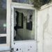 Zerbrochenes Fenster in einer alten Schützenhalle mit Kerben und unordentlicher Umgebung.